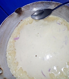 Vegetable oil being spread round the edges of the batter to prevent it from sticking to the pan