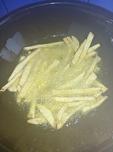 Yam chips in hot oil cooking on a medium heat