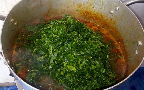 Adding of shredded efo tete (vegetables) to the bubbling content