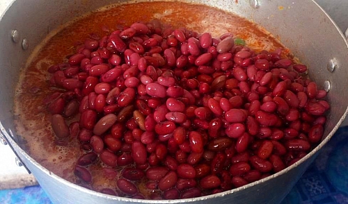 The red beans and rice are being stirred into the content.