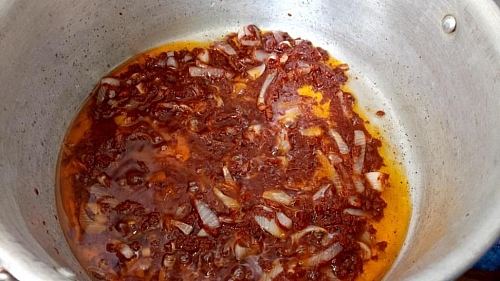 Frying tomato paste with onions for jollof rice recipe
