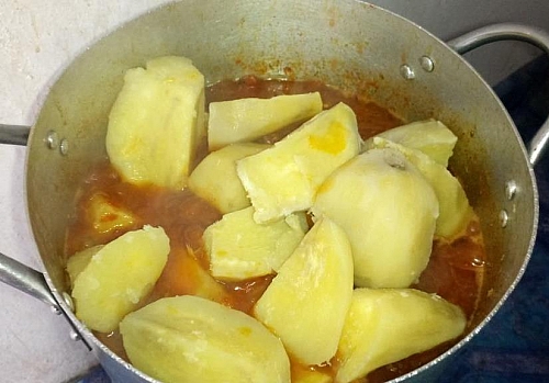 Adding of boiled sweet potatoes to tomato sauce